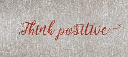 White wall with red text stating "think positive".